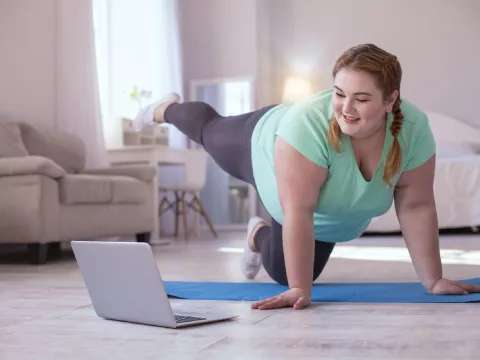 A woman doing a yoga session in front of her computer