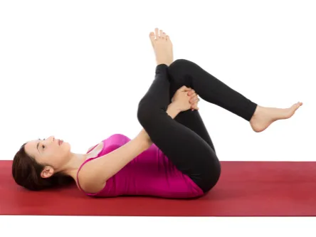 A woman lies on her back, stretching. 