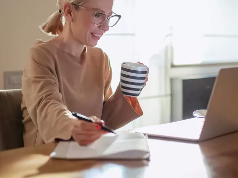 A woman on her computer and taking notes