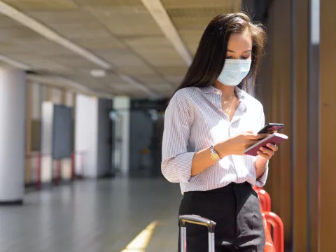 Masked woman checking her phone at an airport