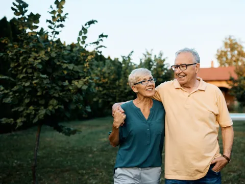 Happy senior couple enjoying while walking embraced in their backyard. 