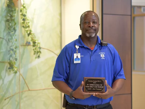 AdventHealth worker, Ken Tramell, holding his award plaque