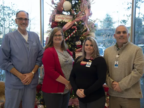 Group of people standing in front of a Christmas tree.
