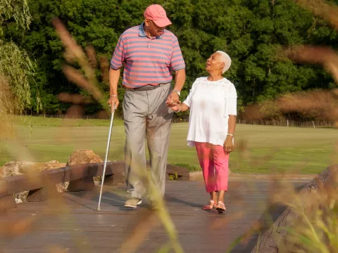 Elderly couple holding hands while walking.