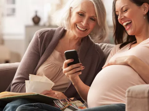 A pregnant woman with her mom looking something on her cell phone