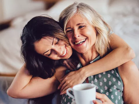 An adult daughter hugs her mother.