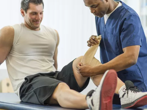 An athlete works with a physical therapist for a knee injury.