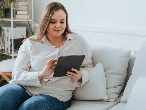 A woman using a tablet on her couch.
