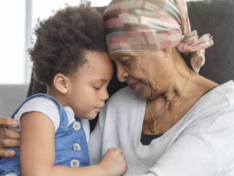 A cancer survivor hugs her grandchild.