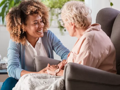A caregiver helps an elderly patient in their home.