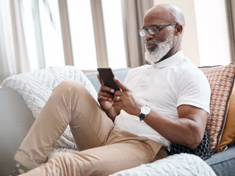 A man checking his phone from the couch. 