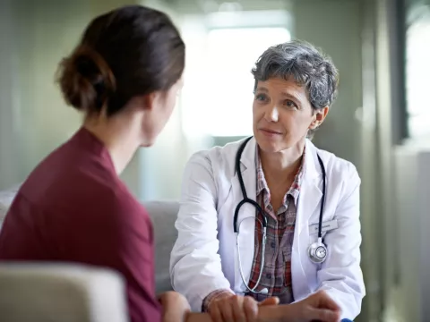 A female doctor comforts a young woman in her office