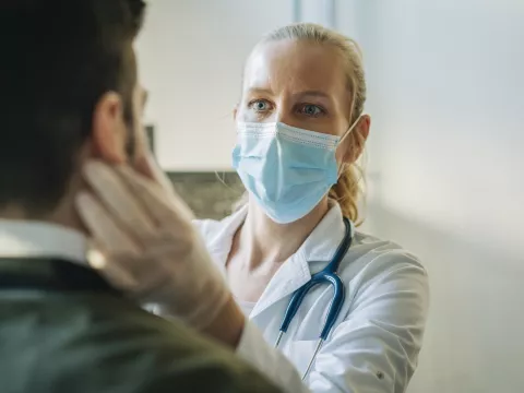 A doctor examines a patient while wearing a mask. 