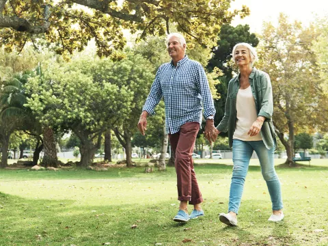 A mature couple walks in the park.