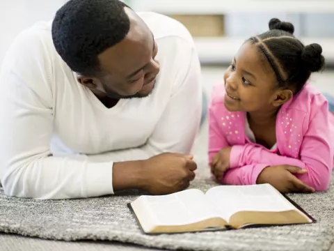 A father and daughter read the Bible together.