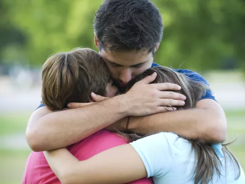 A father hugs his two children.