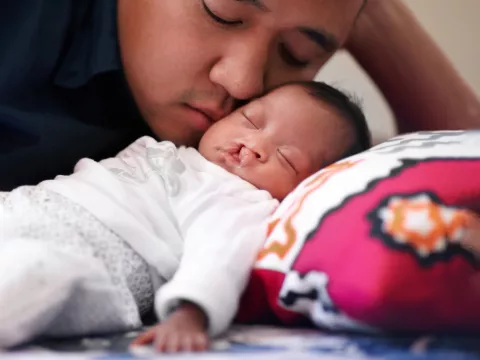 A father cuddling his infant.
