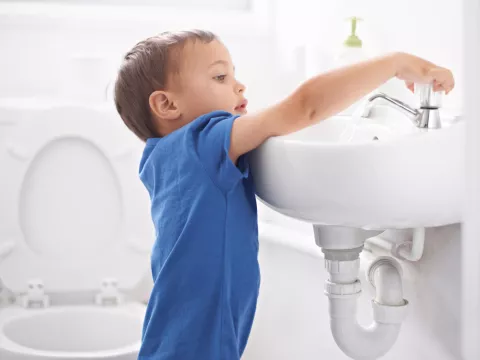 A child turning on the bathroom sink.