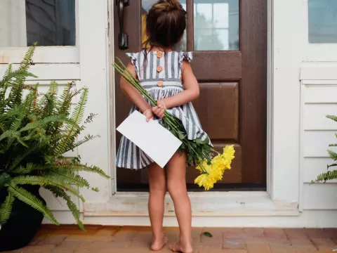 A little girl delivers flowers to a loved one's front door.