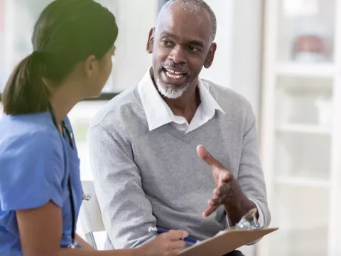 A man asks questions at his appointment with his doctor.