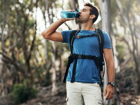 A man drinking water on a hike.