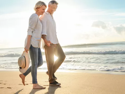 A couple walks on the beach near sunset.