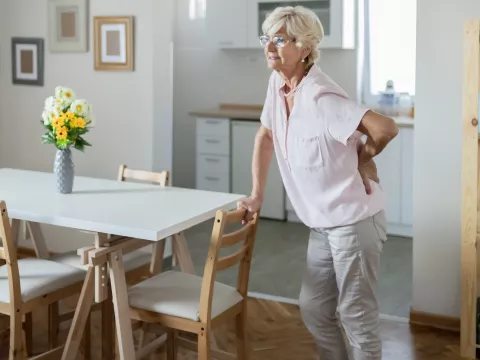 A woman experiencing lower back pain in her home. 