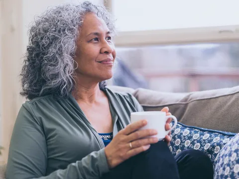 A woman sits by the window drinking tea.