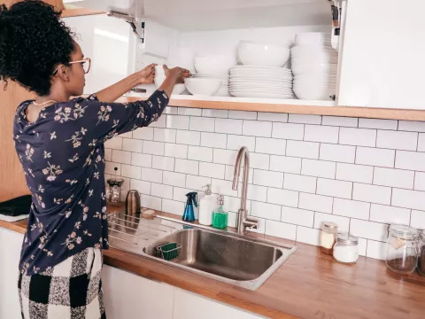 A young adult woman organizing items in her kitchen