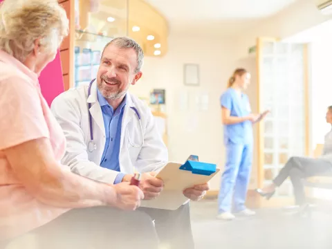 A patient speaks with her doctor in the waiting room.
