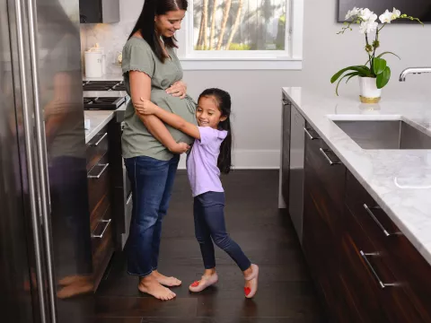A pregnant mom and her daughter in the kitchen.