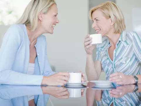 Two women chatting and drinking tea together.