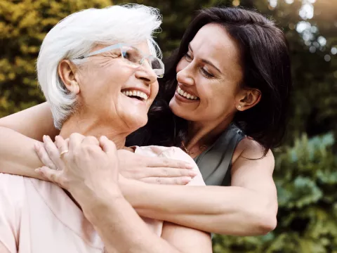 An adult woman hugs her mother.