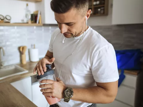 A man making a shake and preparing for a workout.