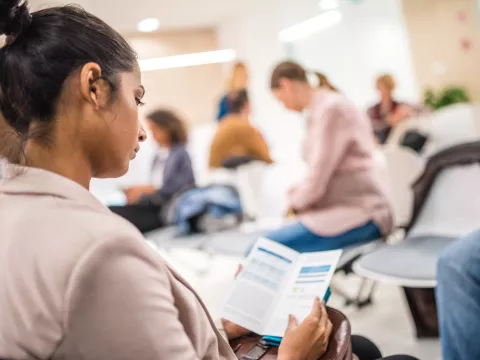 Young Woman Reads a Pamphlet in Waiting Room