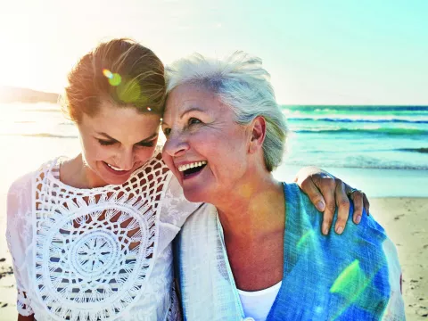 Mother and adult daughter walking on the beach together