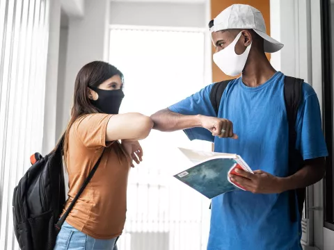 Two teenagers elbow-bumping at school