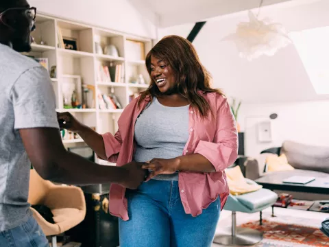 A man and woman holding hands in the living room.