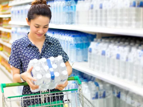 Woman stocking up on bottled water at the grocery store.