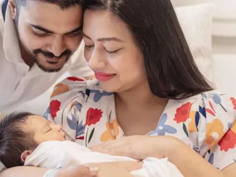Middle Eastern mother and father smiling at newborn