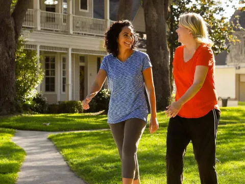 Two women walking and smiling in a neighborhood