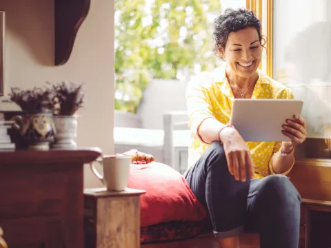 Middle-aged woman smiling at home with tablet