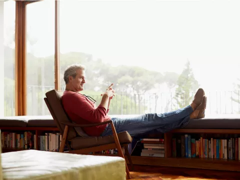 A man sits by a window at home