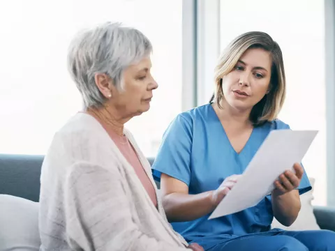 Older female patient looking at a document with her nurse