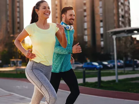 Couple running outside in the city during sunset.