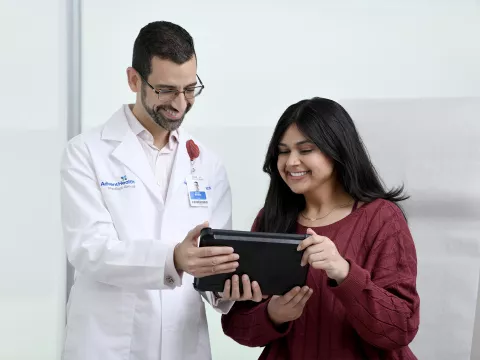 A Young woman looks at a tablet with a physician.
