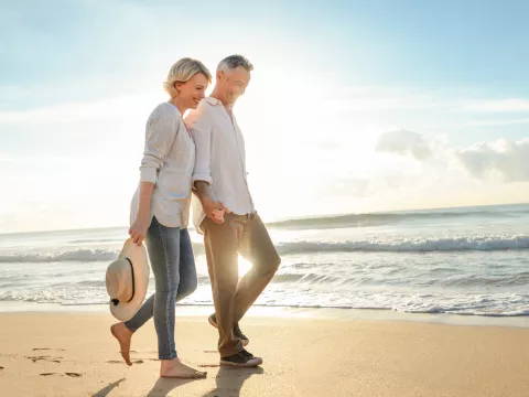 An older couple walks the beach to stay healthy.