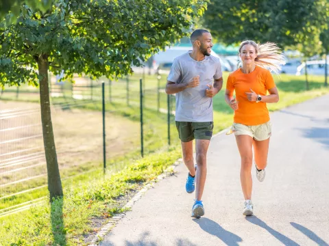 A man and woman running outdoors on a sunny day