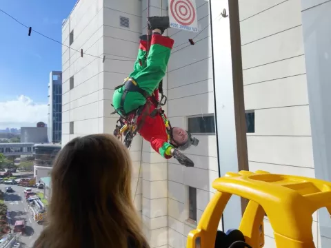 A deputy dressed as an elf rappels from the children's hospital roof to wave to patients inside.