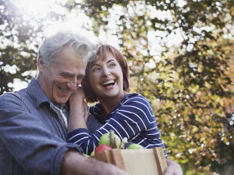Senior couple smiling and embracing after picking up some apples